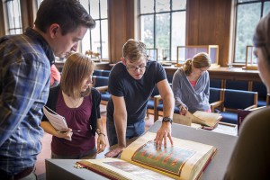 People gather around manuscripts in library